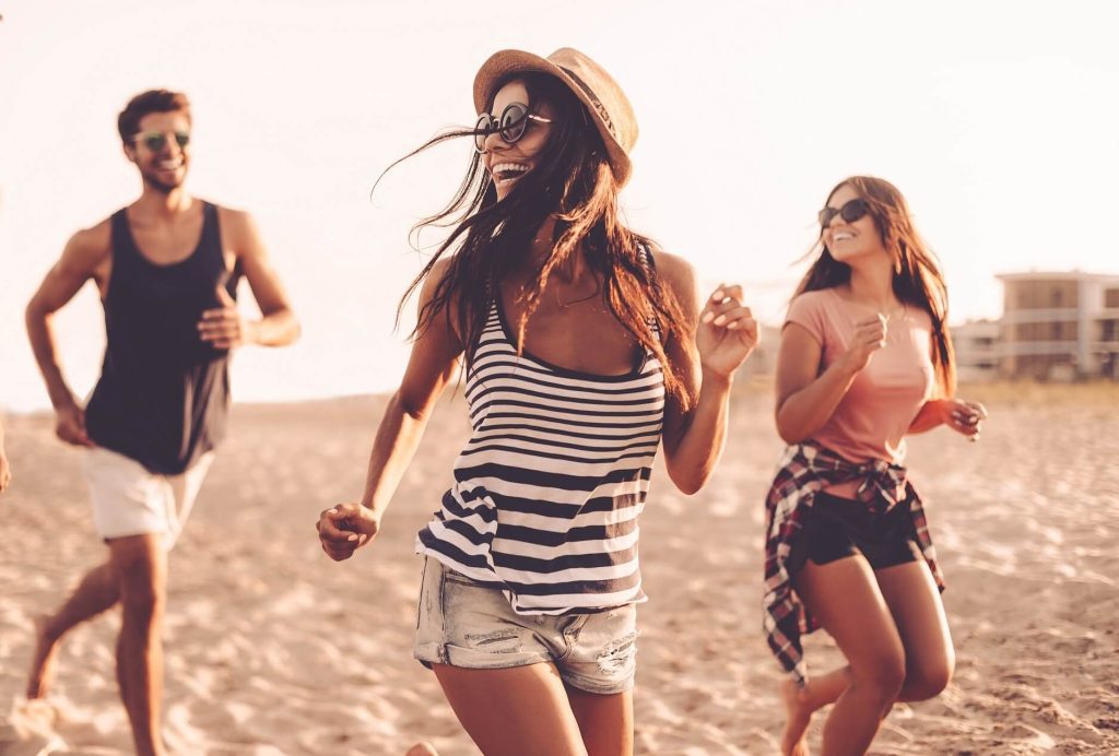 Giovani che corrono e si divertono sulla spiaggia al tramonto.