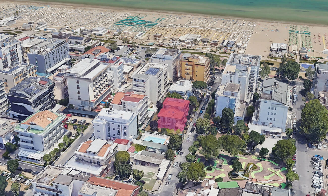 Vista aerea di una località balneare con edifici e spiaggia attrezzata.