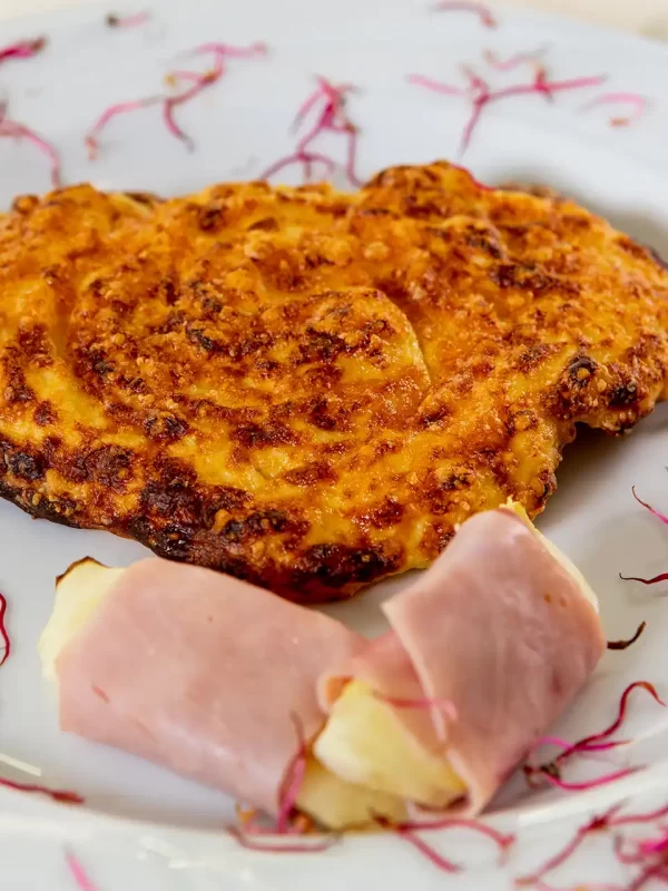 Frittata di riso con contorno di prosciutto e formaggio su piatto decorato.