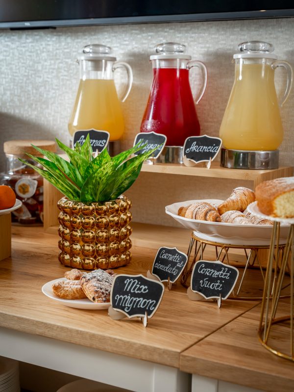 Buffet della colazione con succhi di frutta e varietà di cornetti.