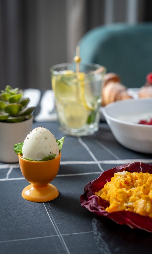 Colazione con uovo sodo, uova strapazzate, succulenta e bicchiere d'acqua con limone.