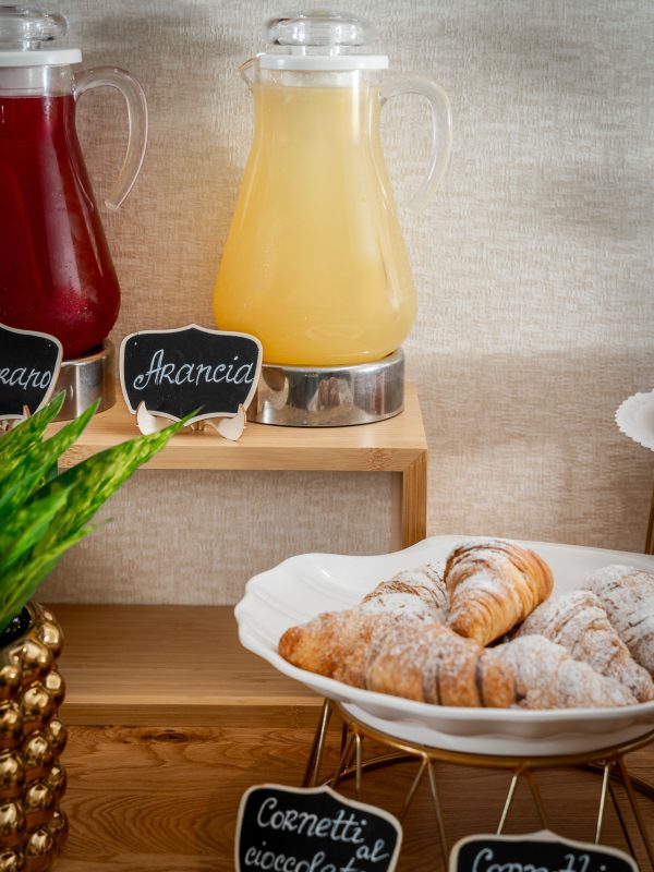 Caraffe di succhi e piatto di cornetti su un tavolo da buffet per colazione.
