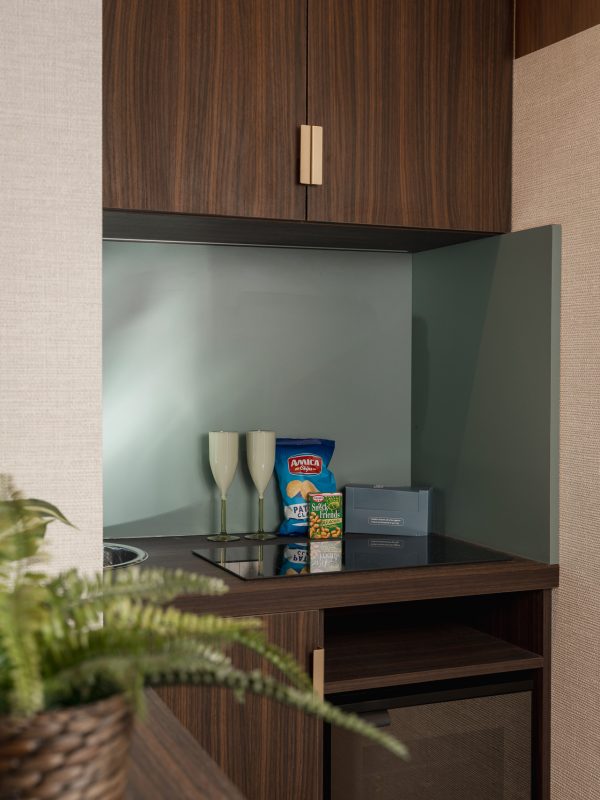 Piccola area cucina con bicchieri, snack e mobili in legno scuro.