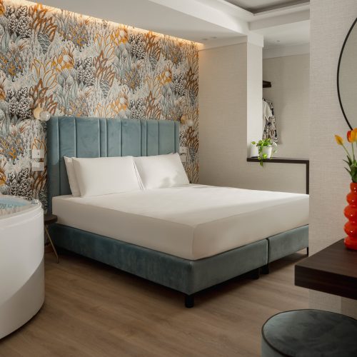 Camera d'albergo moderna con carta da parati vivace, letto matrimoniale e vasca da bagno circolare.