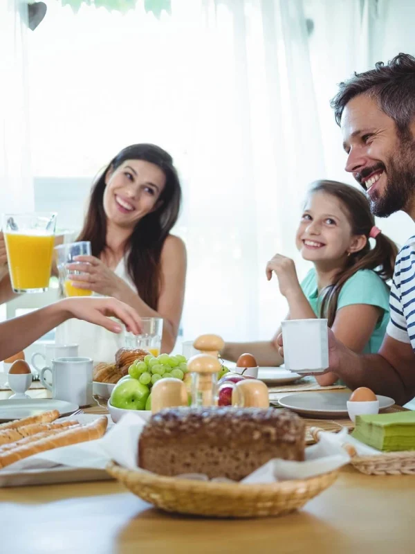 Eine vierköpfige Familie genießt gemeinsam ein Frühstück am Tisch.