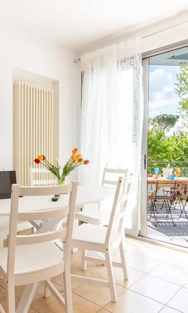 Sala moderna e luminosa con tavolo da pranzo e accesso al balcone.