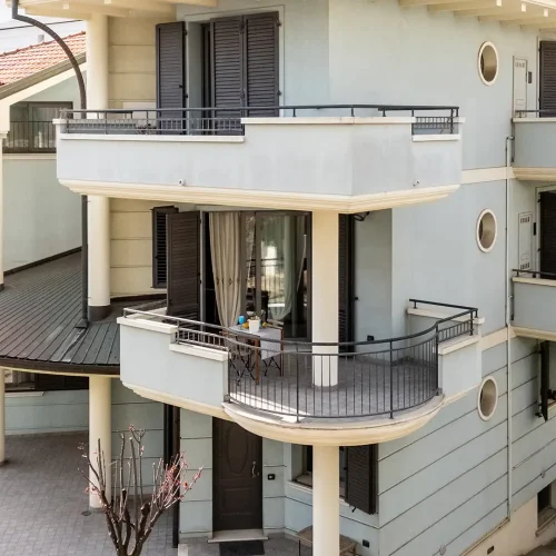 Edificio residenziale moderno con balconi e giardino circostante.