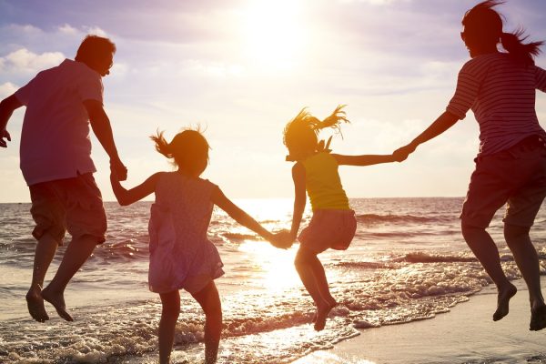 Famiglia felice salta sulla spiaggia al tramonto.