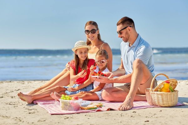 Famiglia che fa un picnic sulla spiaggia in una giornata soleggiata.