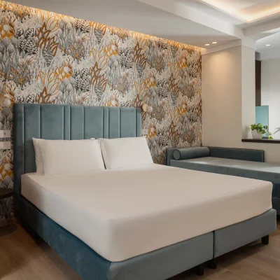 Camera da letto moderna con letto matrimoniale e divano su sfondo di carta da parati floreale.