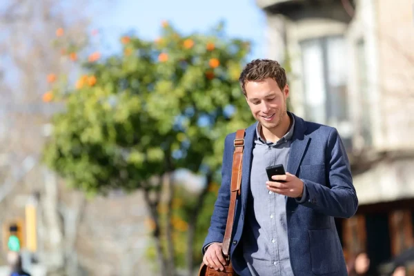 Professionista che consulta lo smartphone mentre cammina in città.