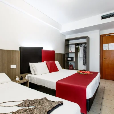 Camera d'albergo moderna con due letti, TV a parete e decorazioni colorate.